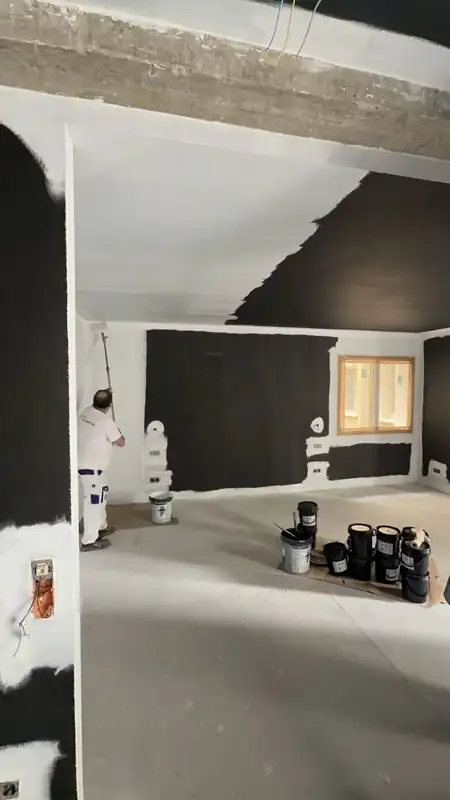 Pintor aplicando pintura apantallante en una sala en obra