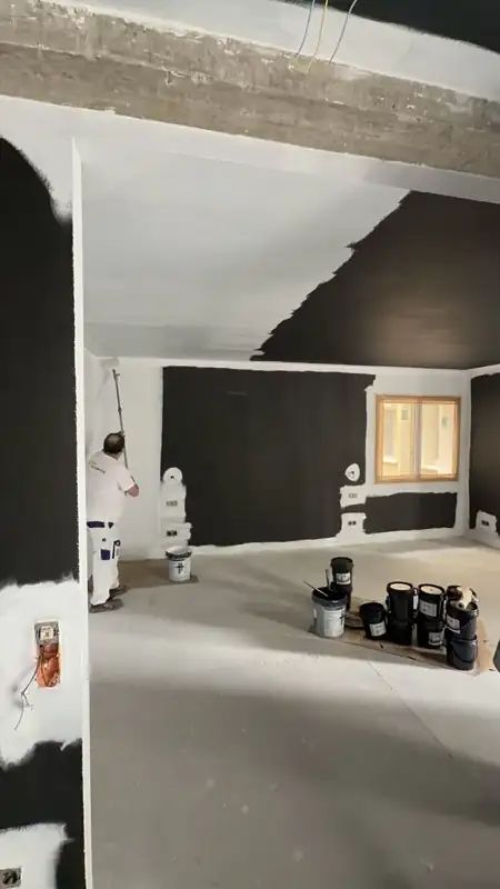 Pintor aplicando pintura apantallante en una sala en obra